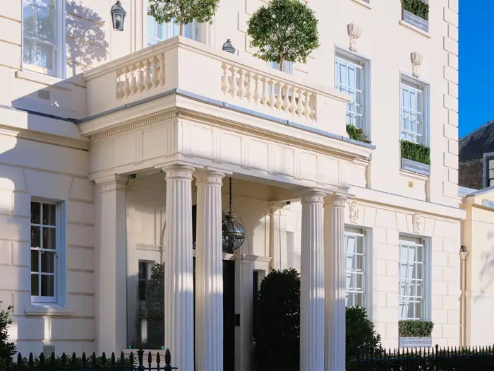 A white stucco Mayfair townhouse with a columned portico