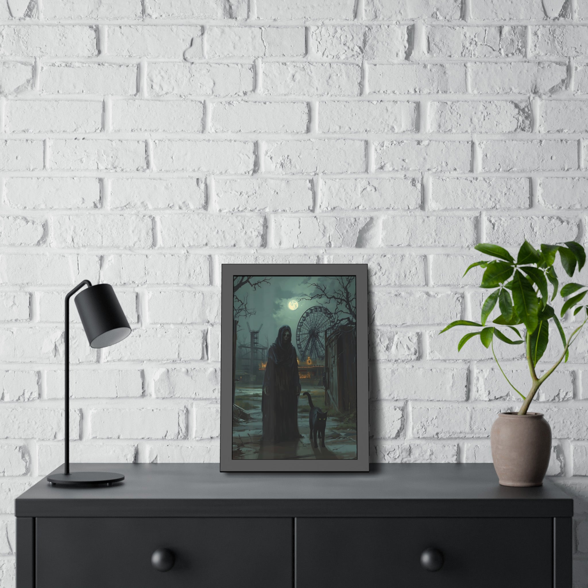 Framed artwork of a silhouette by a Ferris wheel on a white brick wall with a black lamp and plant.
