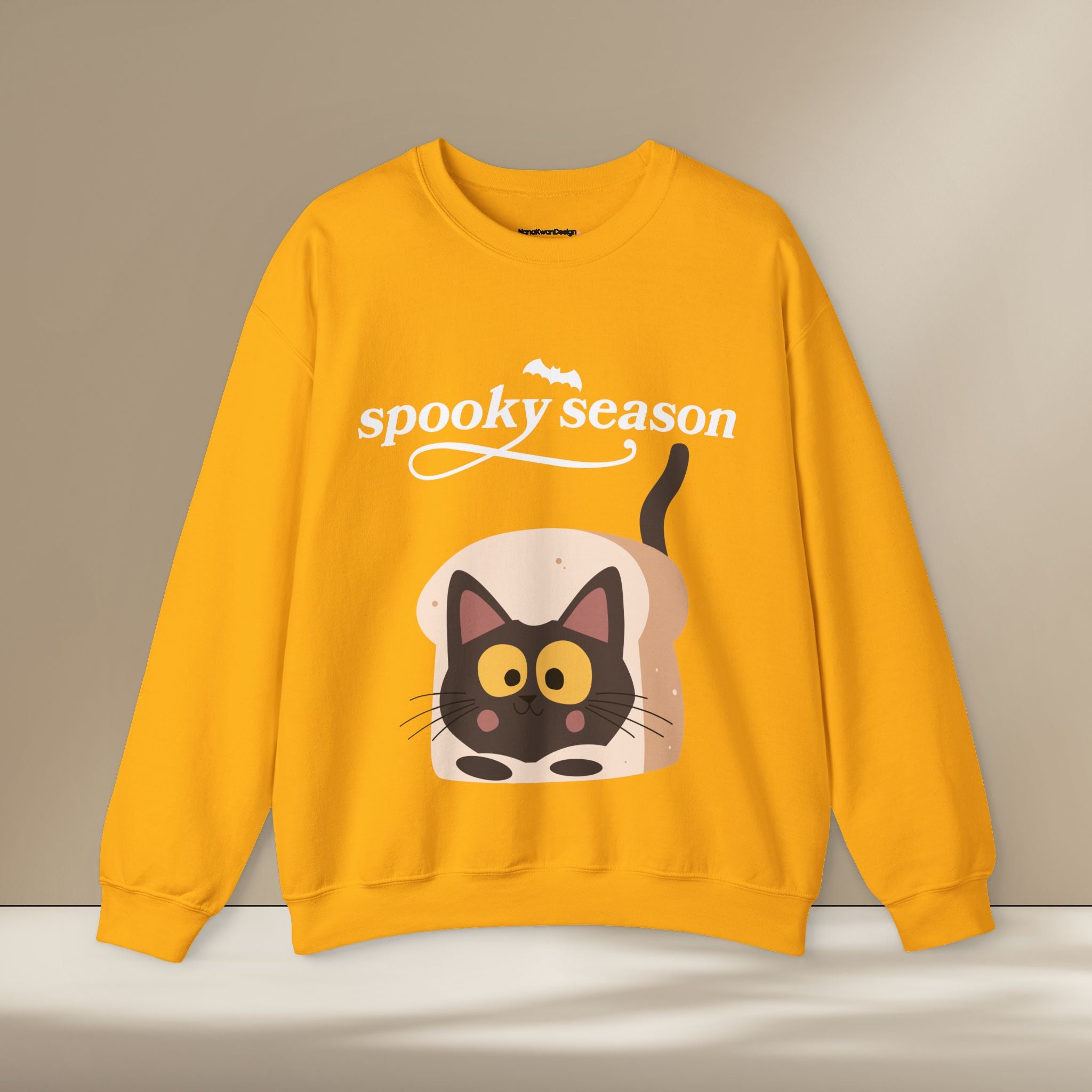 Yellow sweatshirt with a cat graphic and 'spooky season' text on a beige background