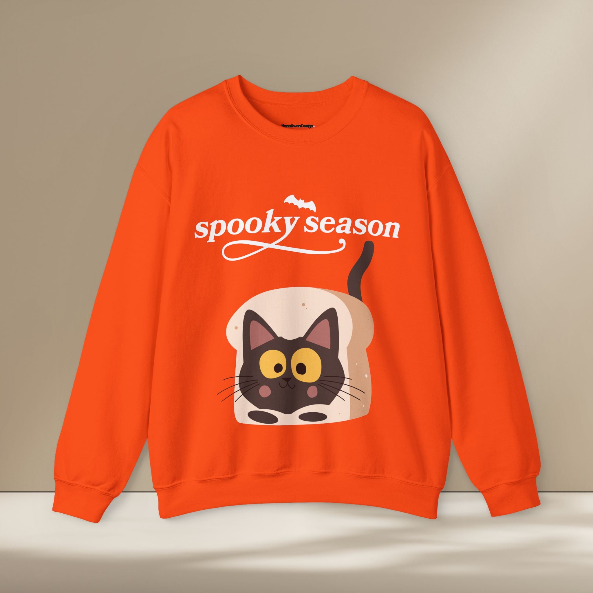 Orange sweatshirt with a cat design and 'spooky season' text on a beige background