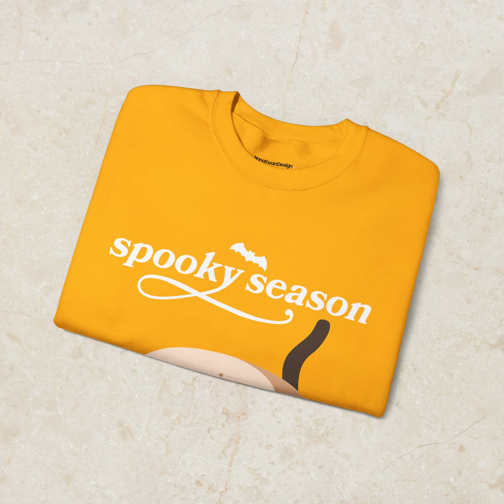 Yellow sweatshirt with 'spooky season' text on a beige background